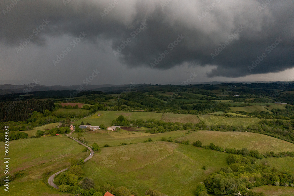 Aerial view of a countryside landscape with heavy cloud and storm rolling on fields and villages. 