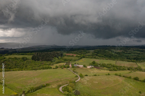 Aerial view of a countryside landscape with heavy cloud and storm rolling on fields and villages. 