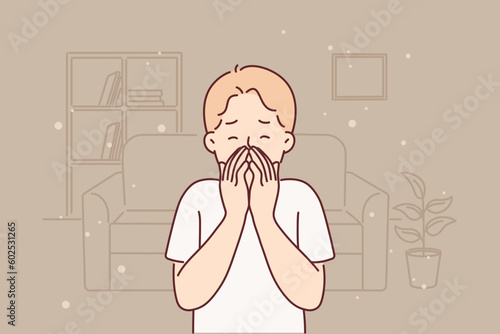 Little boy allergic to dust sneezes and suffers from runny nose standing in untidy room