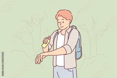 Man uses anti-mosquito spray while walking in forest or natural park in summer weather