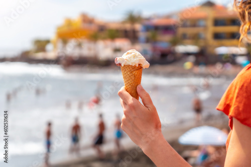 Hand of a tourist woman smiling with a hat eating an ice cream on the beach of Valle Gran Rey in La Gomera, Canary Islands