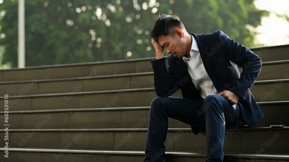 Image of upset man employee sitting on stairs outside office building, financial crisis, unemployed concept Image of upset man employee sitting on stairs outside office building, financial crisis, unemployed concept