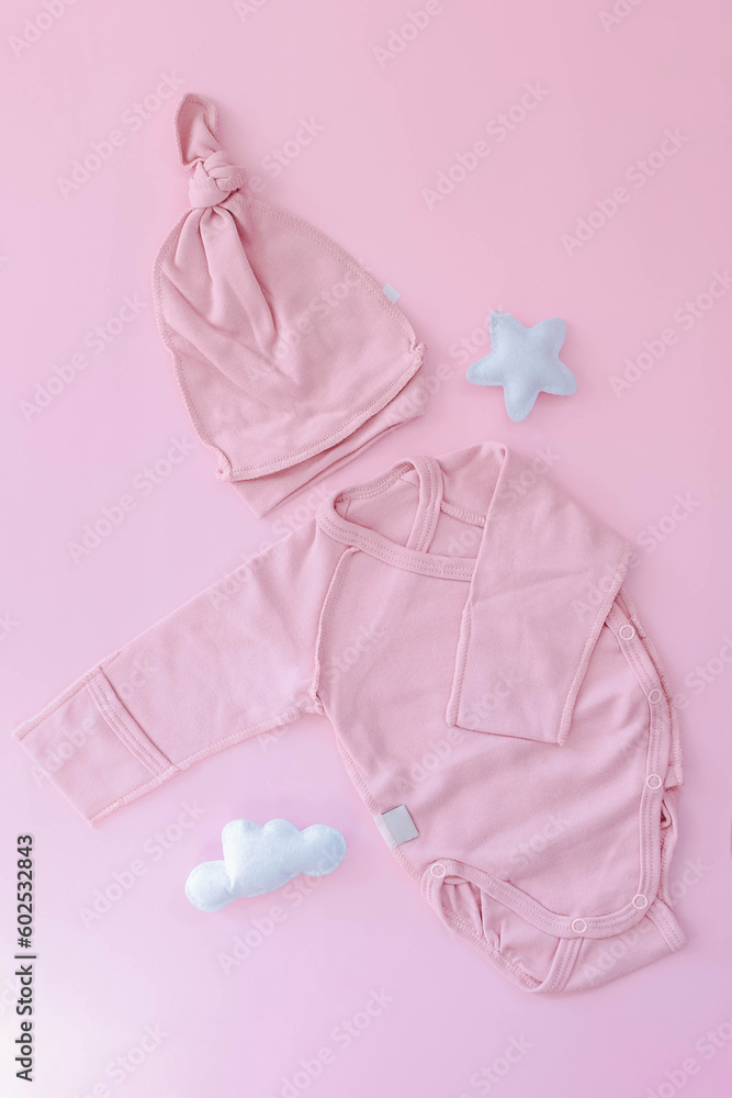 A pink suit for a newborn lies on a pink background. Cap and bodysuit. Clothes for newborns. Pregnancy. Waiting for the girl. A pink suit for a newborn lies on a pink background. Cap and bodysuit. Clothes for newborns. Pregnancy. Waiting for the girl.