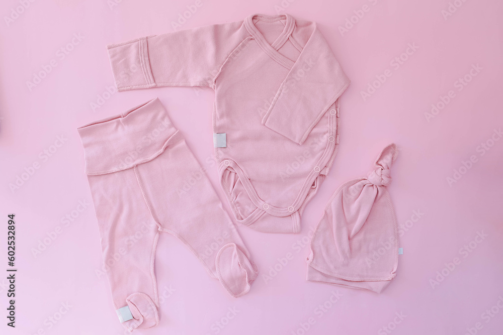 A pink suit for a newborn lies on a pink background. Clothes for newborns. Pregnancy. Waiting for the girl. A pink suit for a newborn lies on a pink background. Clothes for newborns. Pregnancy. Waiting for the girl.
