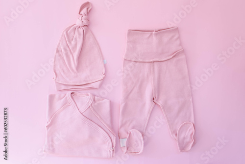 A pink suit for a newborn lies on a pink background. Clothes for newborns. Pregnancy. Waiting for the girl.
