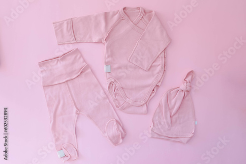 A pink suit for a newborn lies on a pink background. Clothes for newborns. Pregnancy. Waiting for the girl.