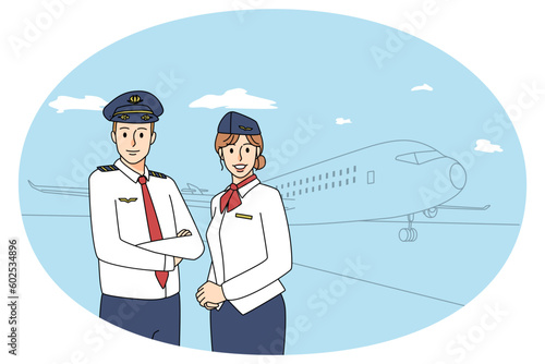 Happy pilot and stewardess near airplane