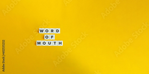 Word of Mouth Marketing (WOM) Term on Block Letter Tiles on Yellow Background. Minimal Aesthetics.