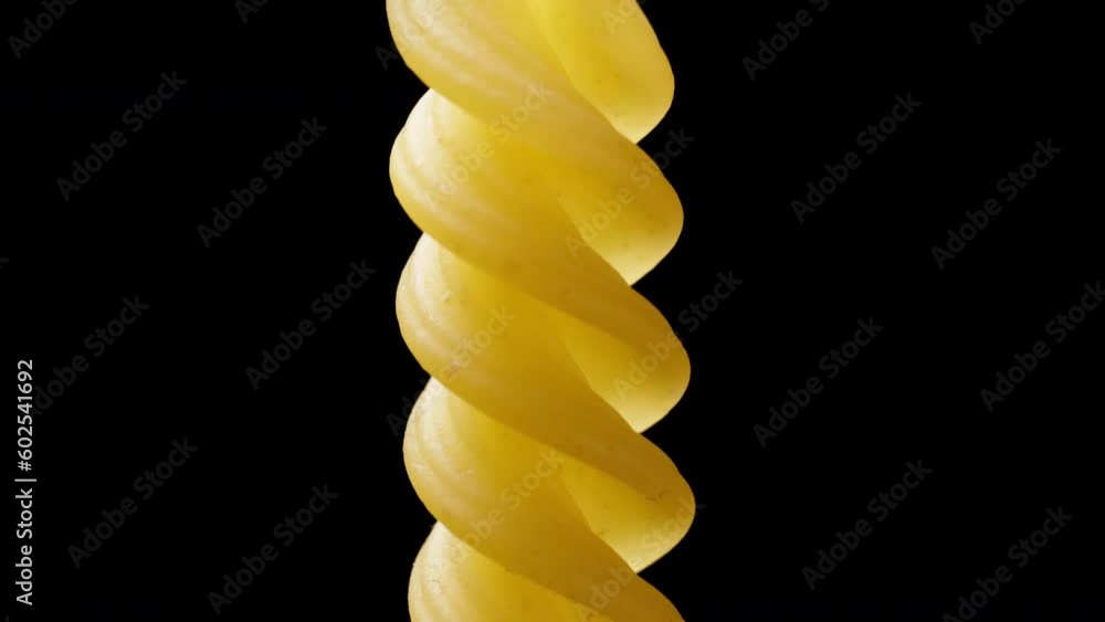 One pasta rotates in a spiral and rises up, macro isolate. One pasta rotates in a spiral and rises up, macro isolate.