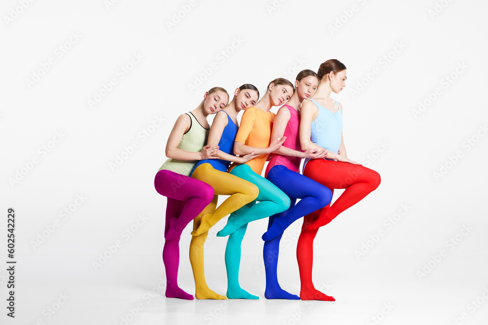 Friendship. Young girls, ballerinas in colorful bodysuits and tights standing closely to each other against grey studio background. Concept of beauty, creativity, classic dance style, contemporary art