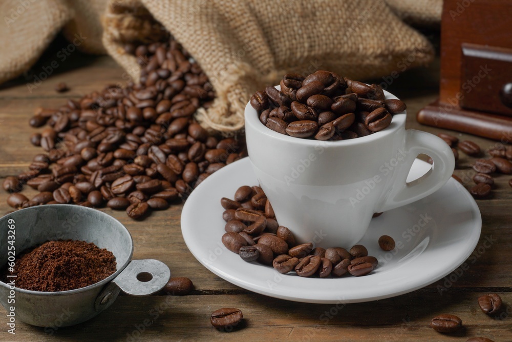 Fototapeta premium Roasted coffee beans in a cup, coffee beans in a sack, and a coffee grinder