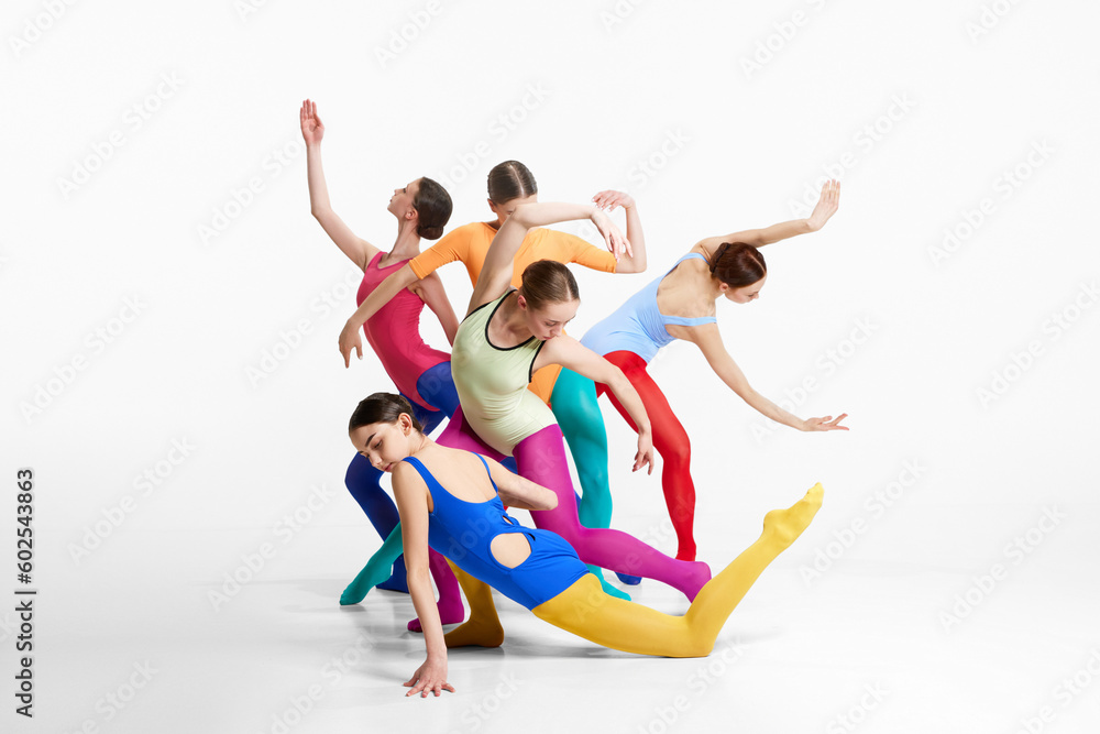 Group of artistic, young girls, ballerinas in multicolored clothes making performance, dancing against grey background. Concept of beauty, creativity, classic dance style, elegance, contemporary art