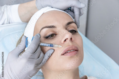 A cosmetologist in medical gloves fills women s wrinkles with hyaluronic acid