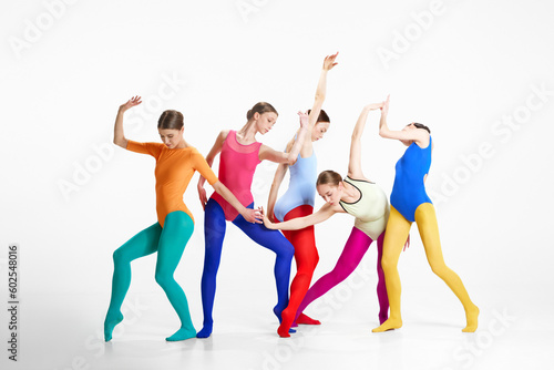 Expressive movements. Young stylish girls, ballet dancers in bright clothes making performance against grey background. Concept of beauty, creativity, classic dance style, elegance, contemporary art