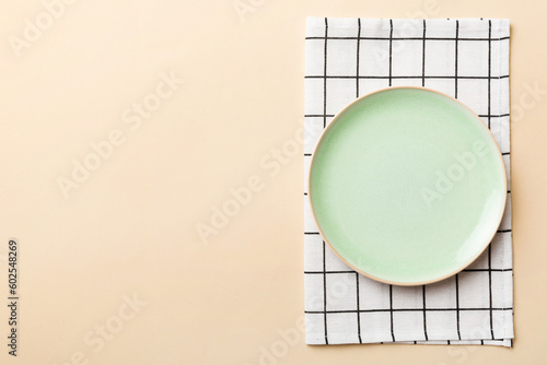 Top view on colored background empty round green plate on tablecloth for food. Empty dish on napkin with space for your design