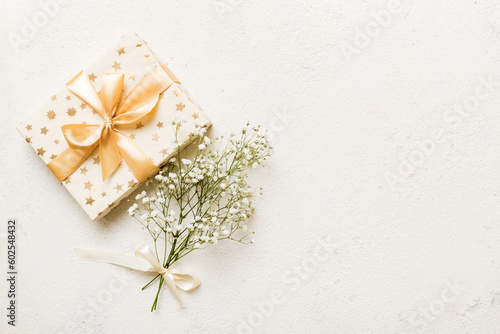 Gift or present box and flower gypsophila on light table top view. Greeting card. Flat lay style with copy space