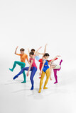 Group of talented, artistic female ballet dancers in bright, multicolored clothes performing, dancing against grey studio background. Concept of beauty, creativity, classic dance, contemporary art