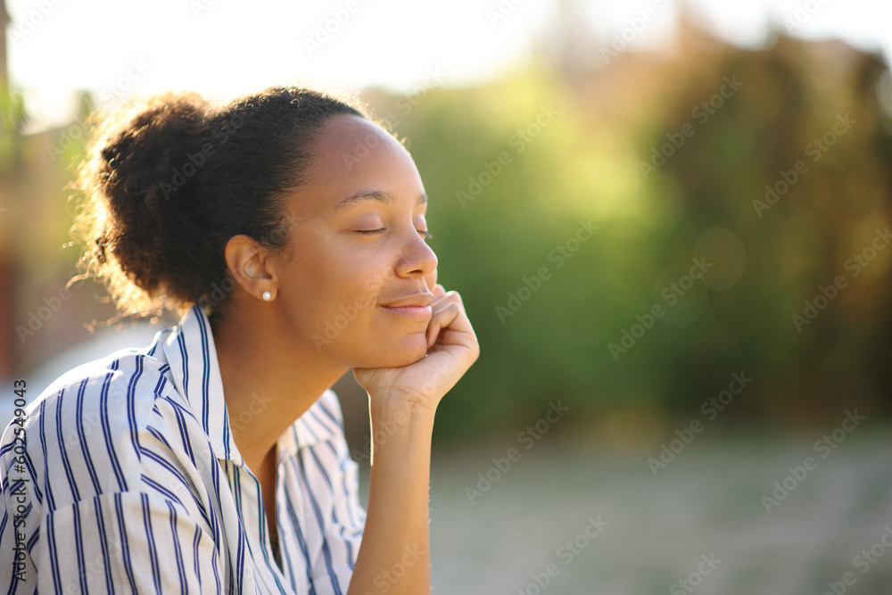 Black relaxed woman resting in a park - obrazy, fototapety, plakaty 