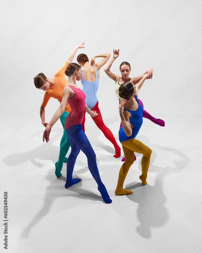 Creative, talented young girls, ballerinas in colorful bright tights dancing against grey studio background. Concept of beauty, creativity, classic dance style, elegance, contemporary art. Top view