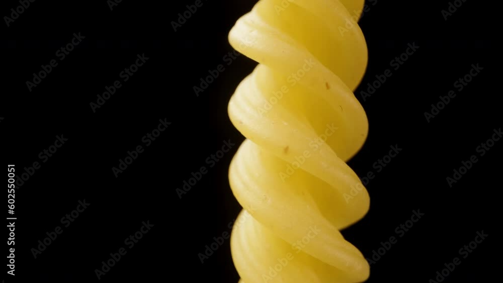 Rotating one fusilli pasta on a black background, macro zoom. Rotating one fusilli pasta on a black background, macro zoom.