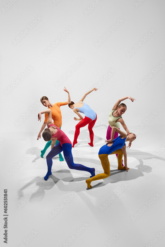 Creative, talented young girls, ballerinas in colorful bright tights dancing against grey background. Game of shadows. Concept of beauty, creativity, classic dance style, elegance, contemporary art