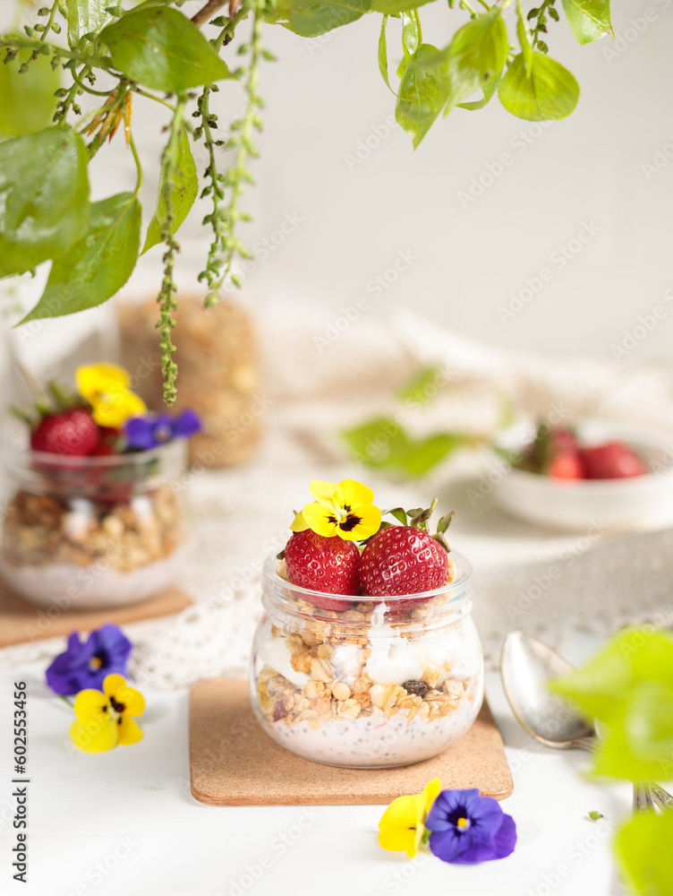 Yogurt with granola, edible flowers and strawberries, vertical light frame, selective focus. Yogurt with granola, edible flowers and strawberries, vertical light frame, selective focus.