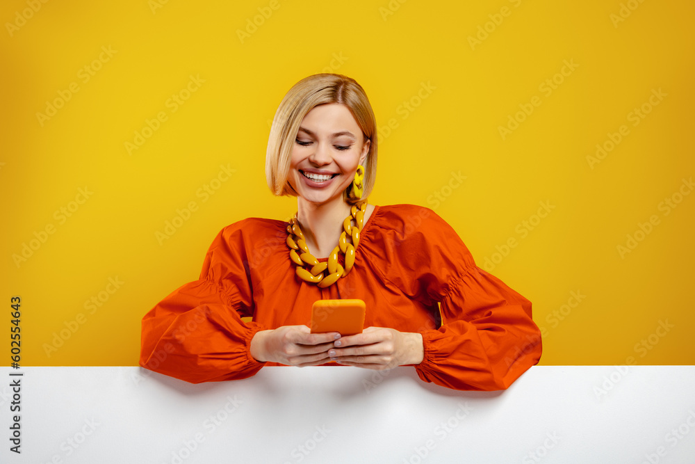 Fashionable young woman using smart phone against yellow background Fashionable young woman using smart phone against yellow background