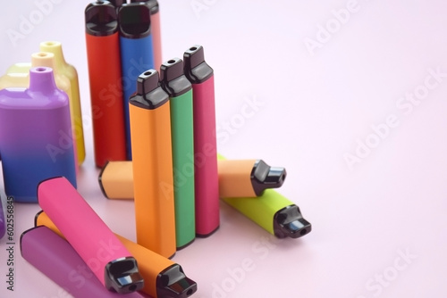 Set of multicolor disposable electronic cigarettes on a pink background.