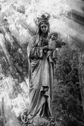 Ancient statue of the Virgin Mary with Jesus Christ in the sunlight. Black and white image.