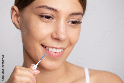 The woman uses brushes to clean the interdental spaces
