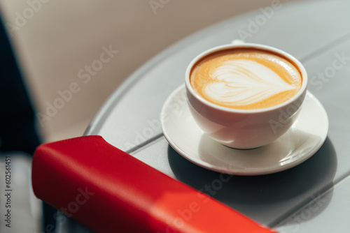 Cup of fresh hot aromatic cappuccino with latte art in shape of heart on a summer terrace