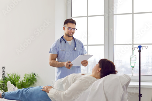 Male nurse at clinic or hospital talks to female patient getting medication through IV line Fototapeta