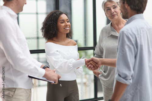 Smiling multiethnic businesspeople shaking hand in office