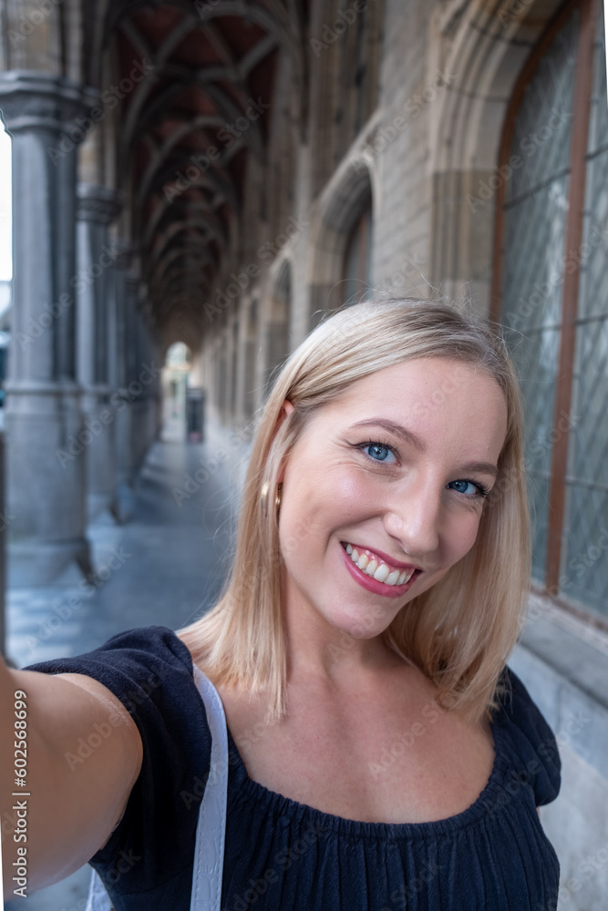 Selfie time, Attractive blonde young funky blogger is making photo for her social networks page. Young happy woman taking selfie in a European city. atmosphere and a beautiful smiling girl. High