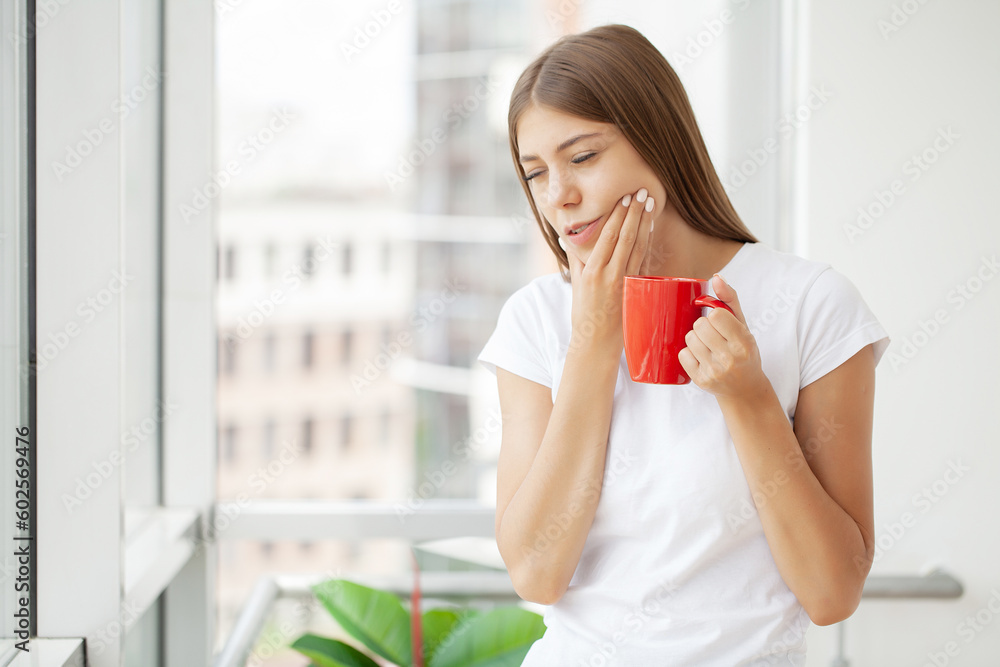 Woman suffering from toothache and touching her cheek while sitting at her desk Woman suffering from toothache and touching her cheek while sitting at her desk