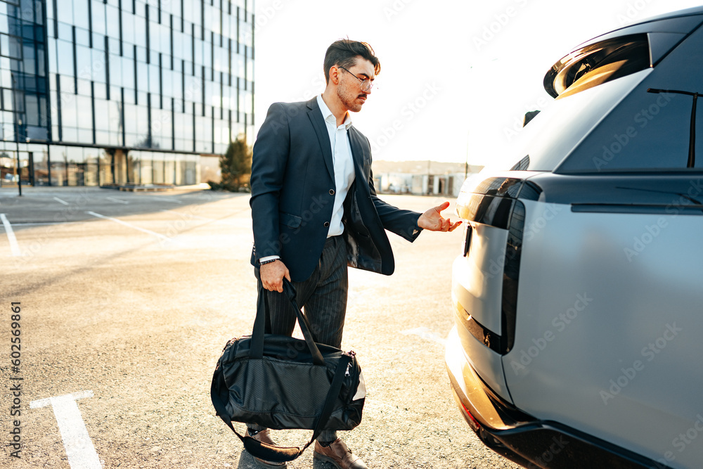 Successful businessman taking luggage from the car trunk Successful businessman taking luggage from the car trunk