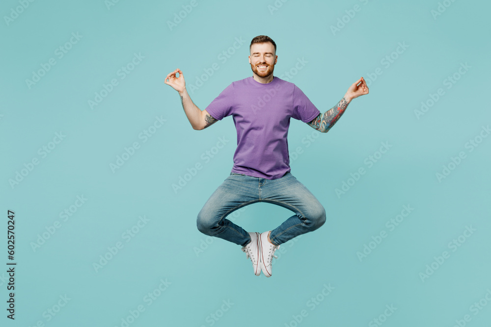 Φωτογραφία Full body young man he wears purple t-shirt jump high hold spreading hands in yoga om aum gesture relax meditate try to calm down isolated on plain pastel light blue cyan background studio portrait