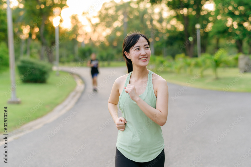 Fit Asian young woman jogging in park smiling happy running and enjoying a healthy outdoor lifestyle. Female jogger. Fitness runner girl in public park. healthy lifestyle and wellness being concept Fit Asian young woman jogging in park smiling happy running and enjoying a healthy outdoor lifestyle. Female jogger. Fitness runner girl in public park. healthy lifestyle and wellness being concept