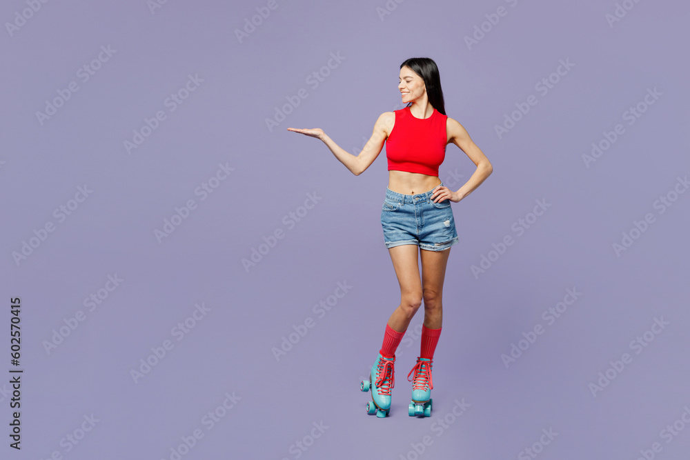 Full body happy young latin woman she wear red casual clothes rollers rollerblading point empty hand aside on area isolated on plain pastel purple background. Summer sport lifestyle leisure concept. Full body happy young latin woman she wear red casual clothes rollers rollerblading point empty hand aside on area isolated on plain pastel purple background. Summer sport lifestyle leisure concept.