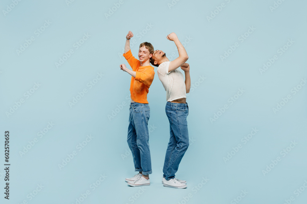 Full body young couple two gay men wear casual clothes together raise up hands dance on party isolated on pastel plain blue color background studio portrait. Pride day june month love LGBTQ concept. Full body young couple two gay men wear casual clothes together raise up hands dance on party isolated on pastel plain blue color background studio portrait. Pride day june month love LGBTQ concept.