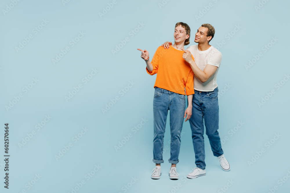 Full body young couple two gay men wear casual clothes together hug point index finger aside on area isolated on pastel plain blue background studio portrait. Pride day june month love LGBTQ concept. Full body young couple two gay men wear casual clothes together hug point index finger aside on area isolated on pastel plain blue background studio portrait. Pride day june month love LGBTQ concept.