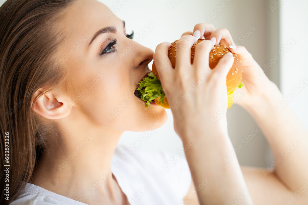 Young woman eating hamburger woman eating junk food Young woman eating hamburger woman eating junk food