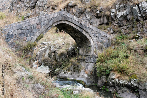 View of old stone bridge over Urut (Miskhan) river on cloudy autumn day. Loriberd fortres, Armenia.