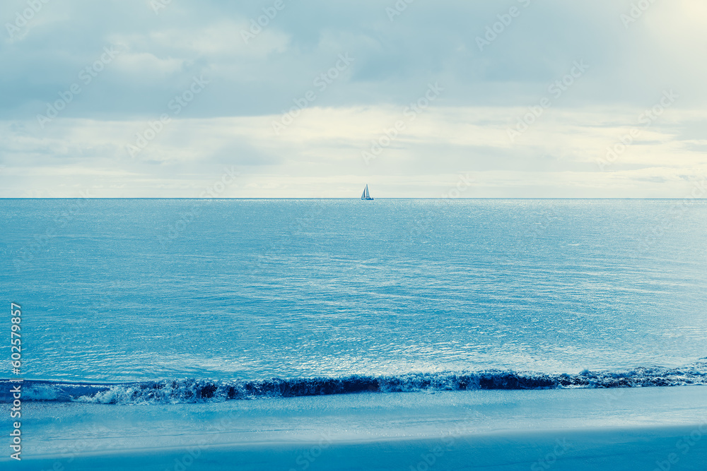 Fototapeta premium Blue sea with sailboat on the horizon . Calm sea scenery 