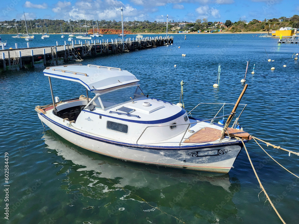Fototapeta premium Boats moored at Mornington Pier in Port Phillip Bay. A popular tourist destination on the Mornington Peninsular. Sunny blue sky day in summer.