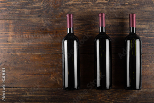 Three bottles of red wine on a wooden background. View from above.