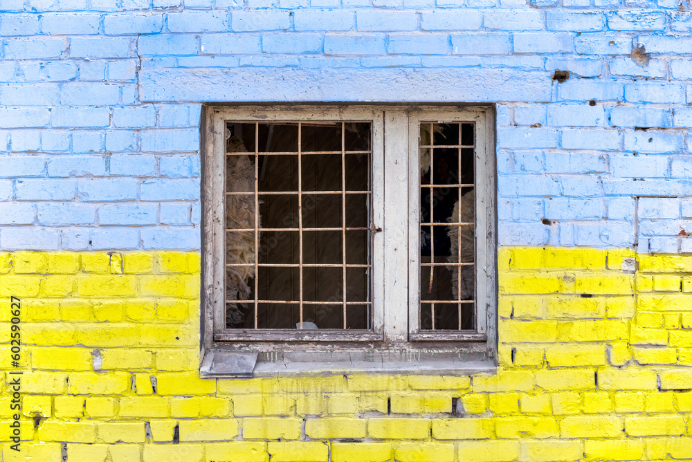 pattern explosion damaged blue yellow house wall with window in Ukraine