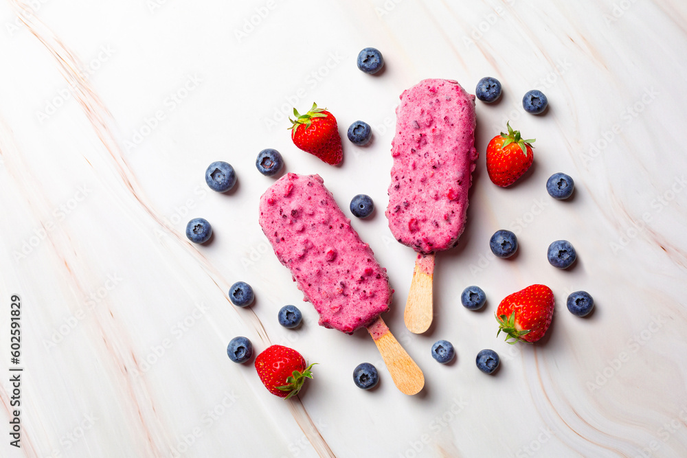 Fruit and berry ice cream on a stick in the, fresh blueberries and strawberries. Popsicle. Top view.  Copy space.