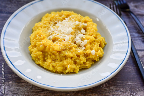  Italian risotto milanese  with parmesan cheese and fresh basil on rustic background