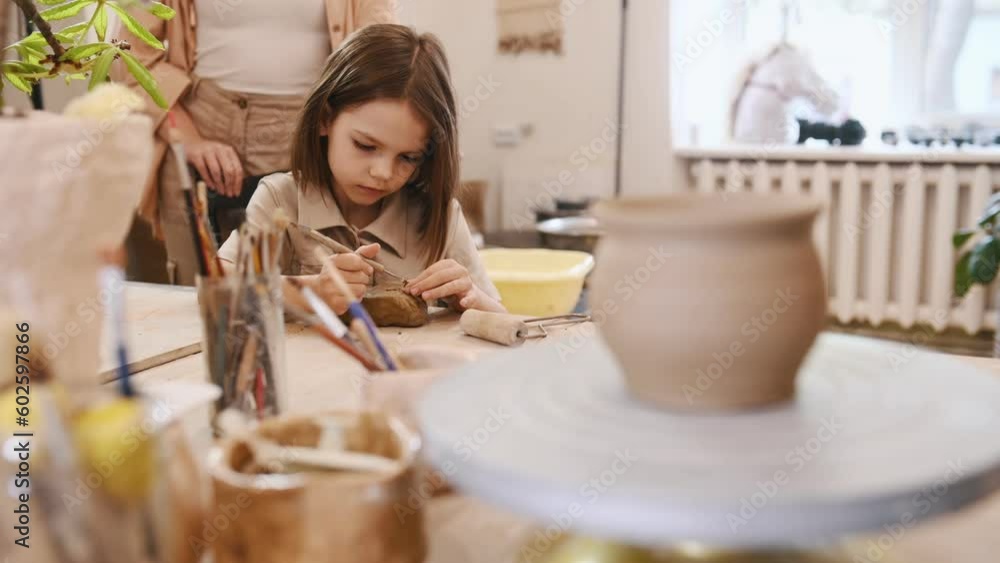 Using the sharp tools to shape the clay. Mother with little girl doing pottery practice. Using the sharp tools to shape the clay. Mother with little girl doing pottery practice.